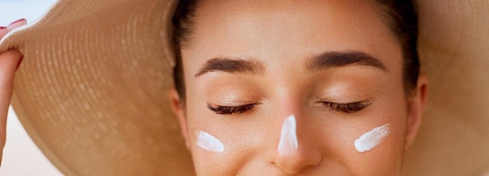 Woman under sunhat with sunscreen on her face