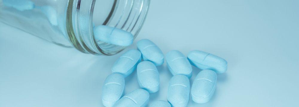 Blue pills spilling out of glass bottle