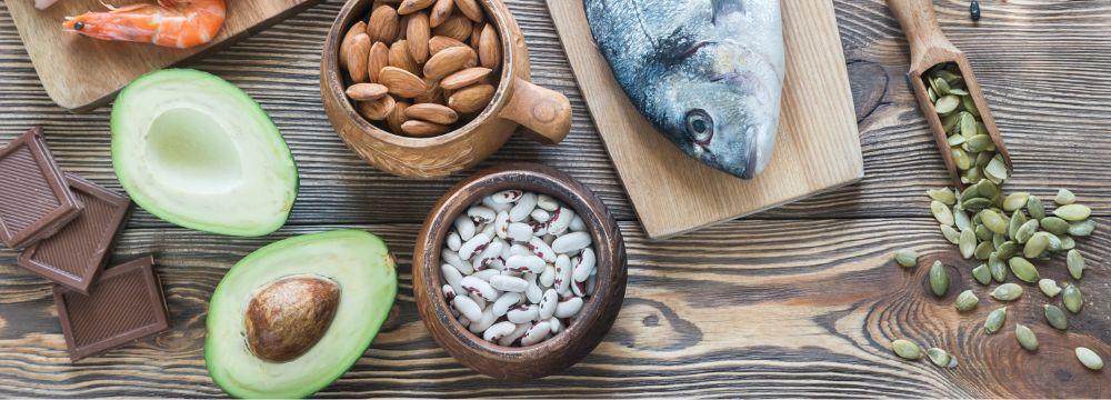 Foods high in zinc scattered on wood. Foods include fish on block, avocado, nuts, shrimp
