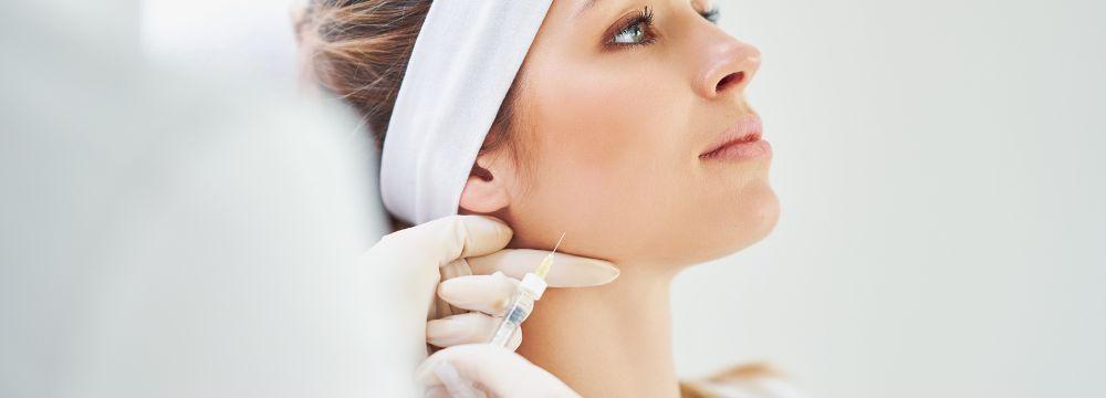 Woman receiving botox on face from injector wearing white gloves