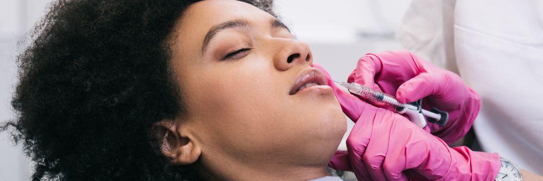 Woman receiving lip filler from injector 